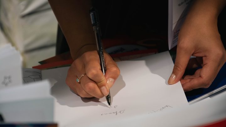 A pair of hands signing a printed form with a pen