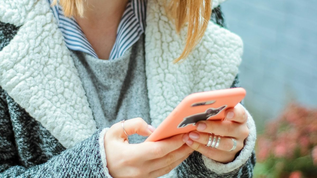 A person reading a message on a phone while sitting at a cafe table